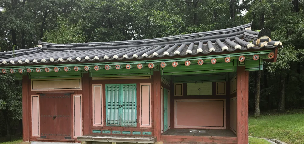 융릉 주변에서 본 기와지붕과 단청, 초록색 문이 있는 전통 건물
