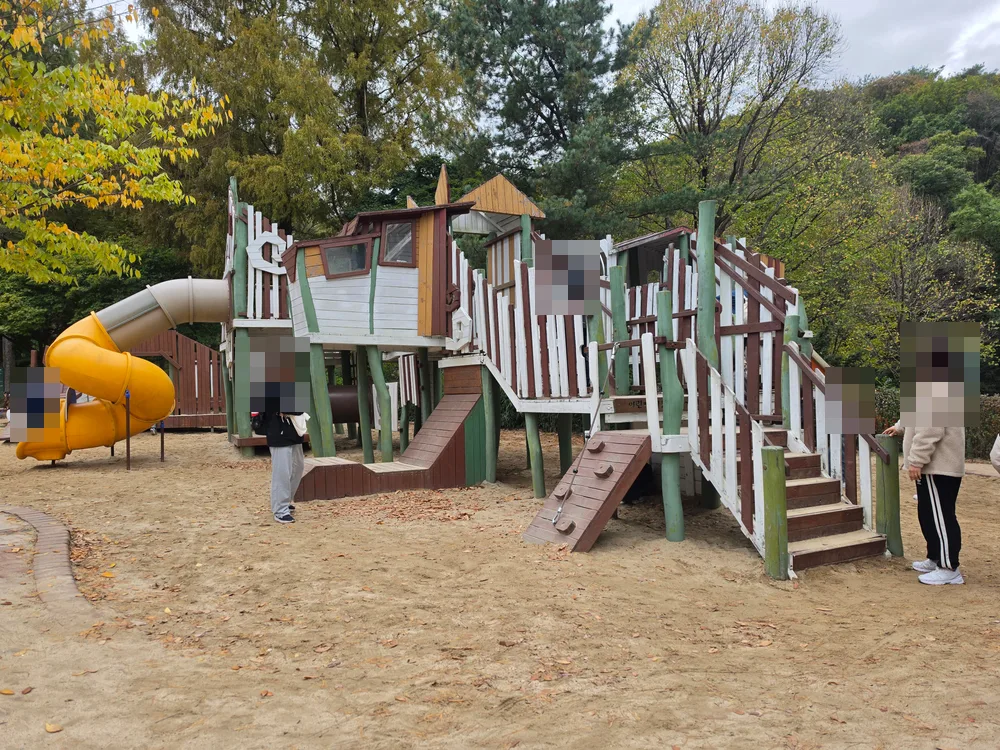나무로 만든 계단과 노란 미끄럼틀이 있는 동물원 놀이터